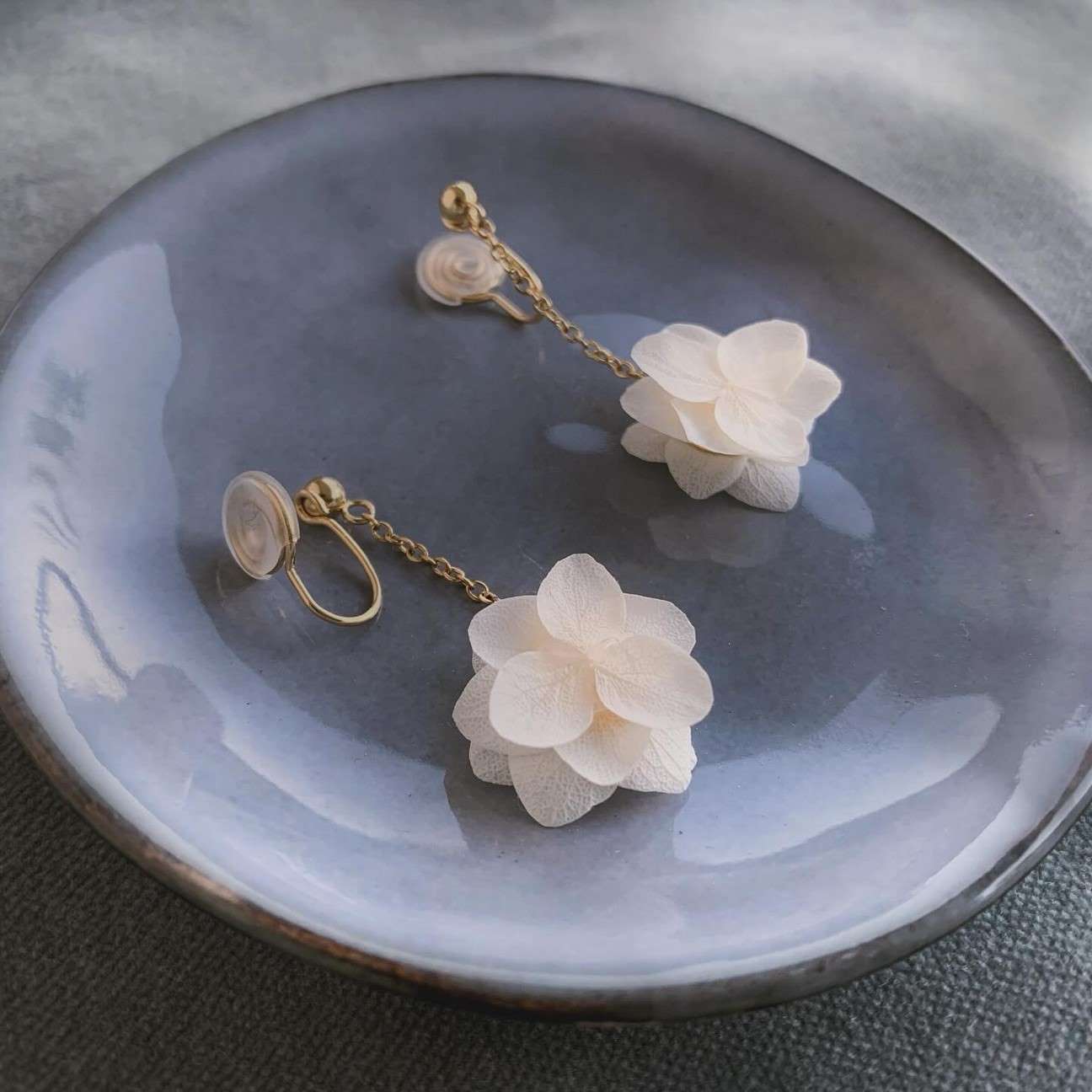 Boucles d'oreilles à clips de la marque Hana&Alice, créées à la main avec des fleurs d'hortensias stabilisés blancs.