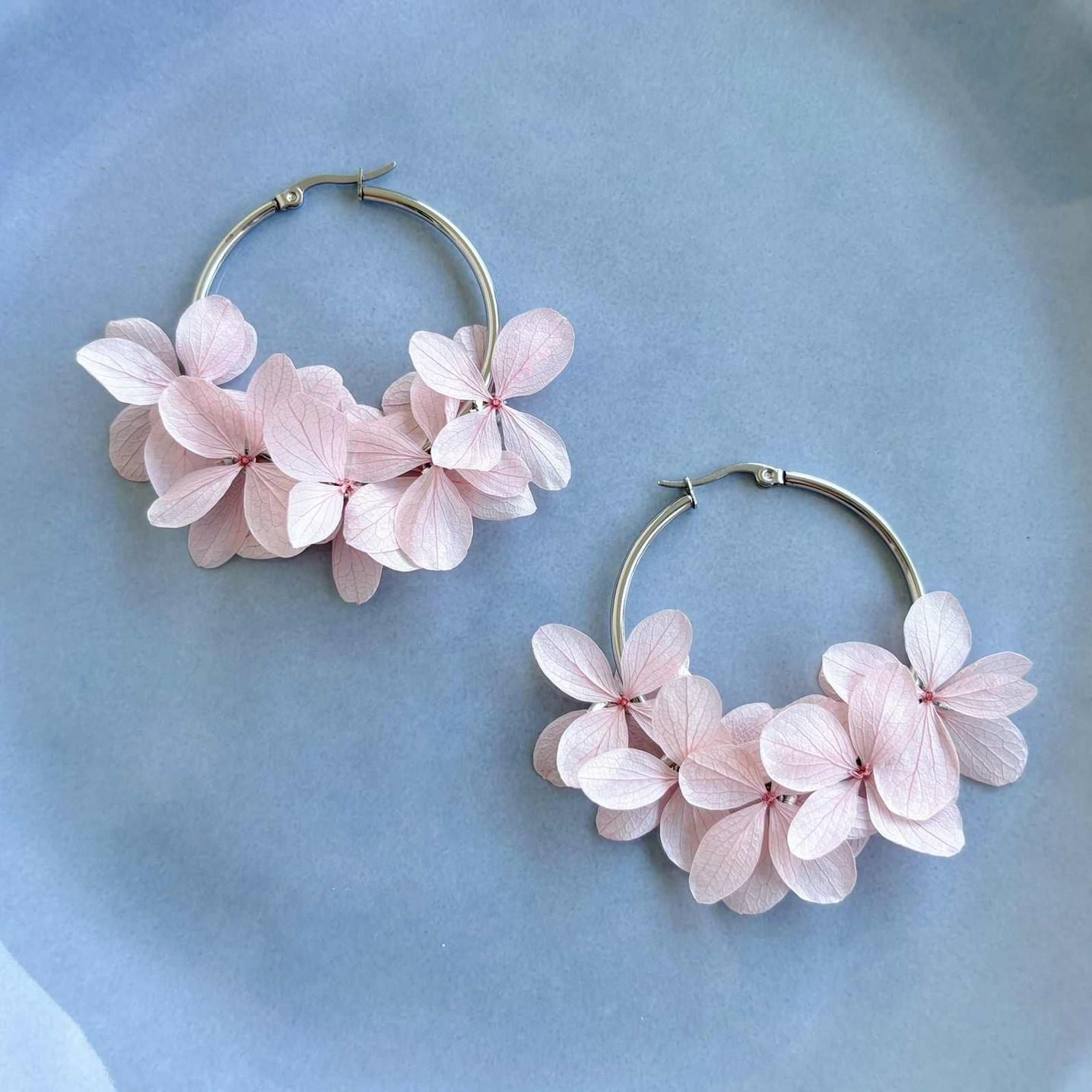 Bijoux mariage créoles en hortensias stabilisés rose clair, une touche florale pour la mariée.