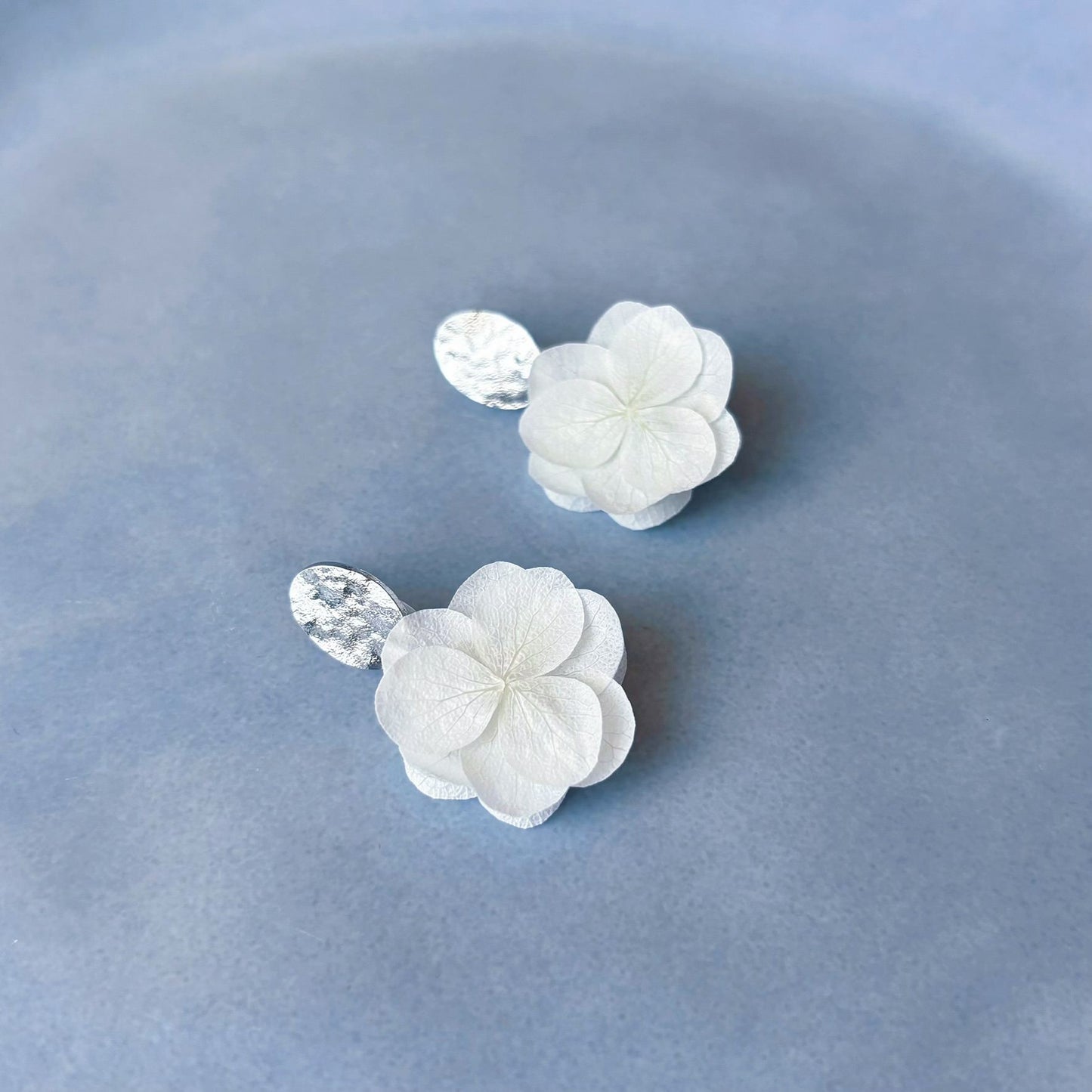 Boucles d'oreilles mariage en fleurs stabilisées blanches et clou d'oreilles martelés texturés, pour apporter une touche naturelle à votre mariage.