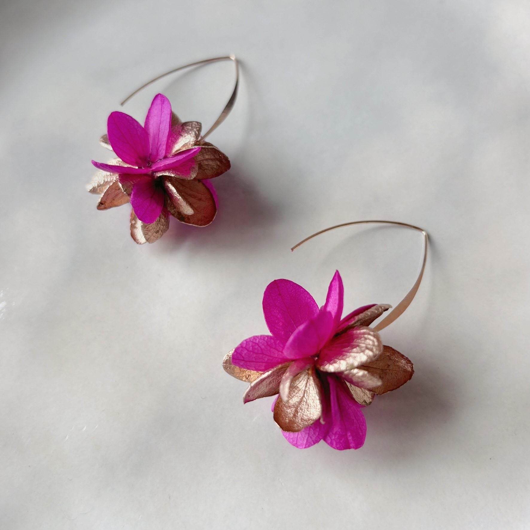 Boucles d’oreilles mariage artisanales, fleurs naturelles fuchsia et dorées, création poétique et raffinée pour cérémonie.