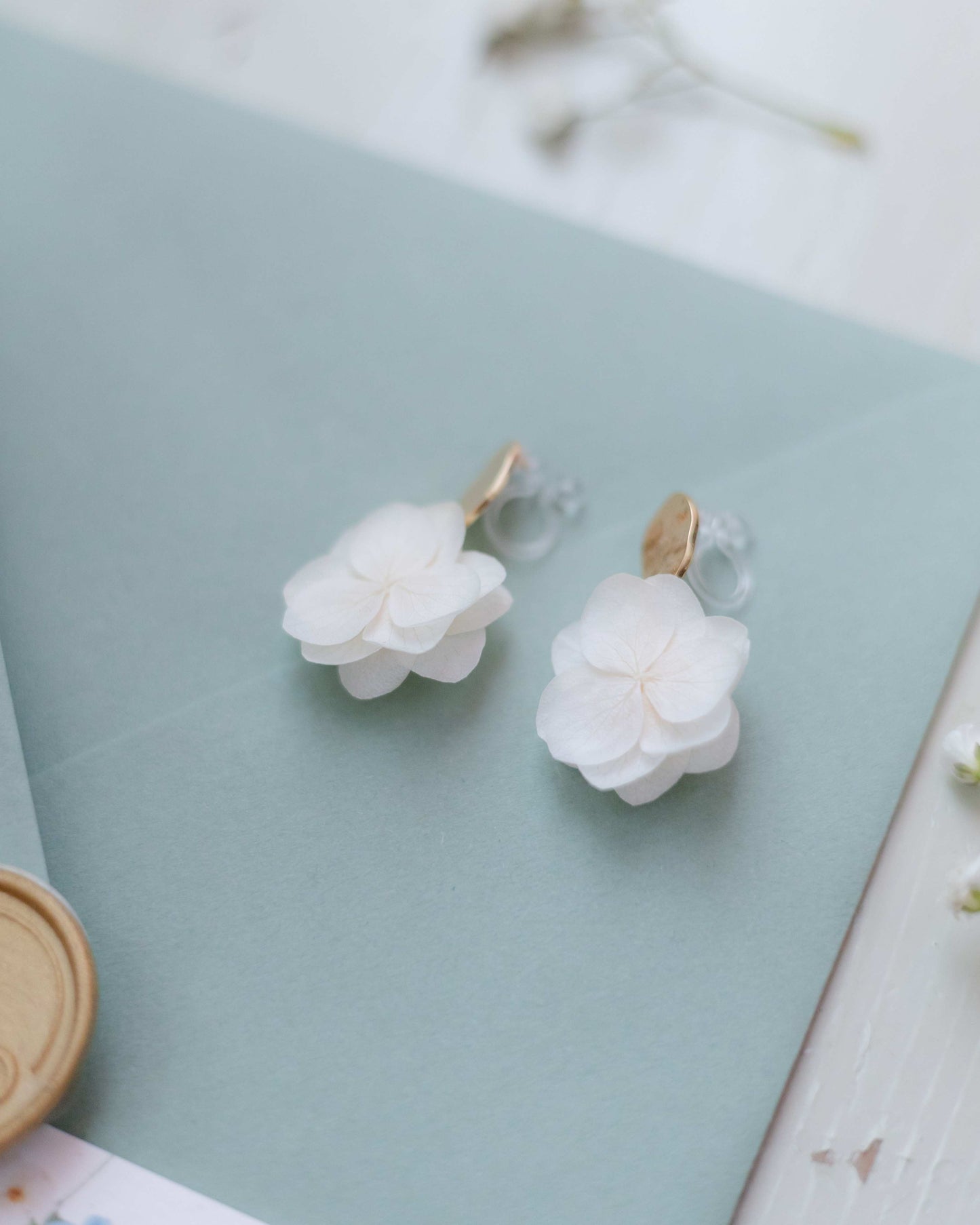 Boucles d'oreilles à clips pour mariage, fleurs d'hortensias stabilisés et doré martelé pour un look raffiné.
