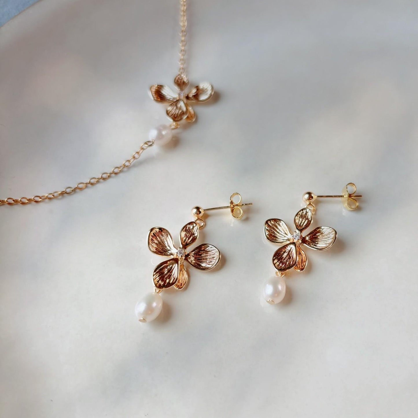 Boucles d’oreilles élégantes pour invitée de mariage, à fleur dorée et perle naturelle.