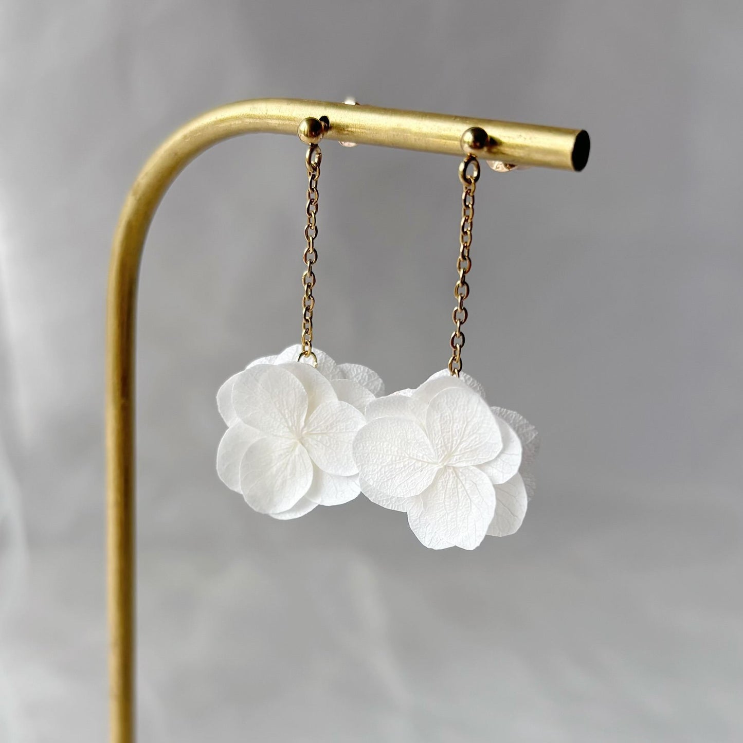 Boucles d'oreilles en perles dorées et fleurs blanches, parfaites pour une mariée élégante.