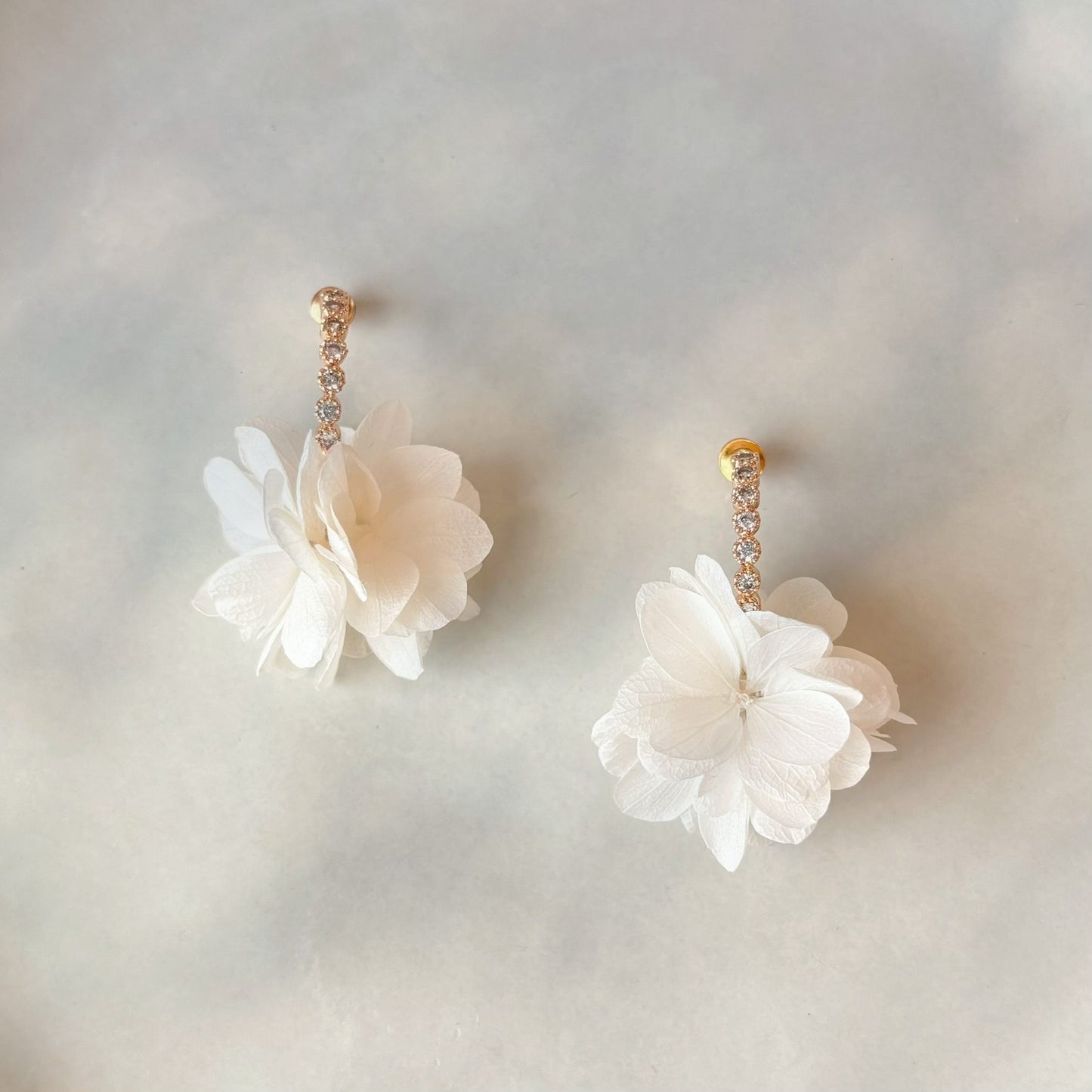 Boucles d’oreilles florales dorées, inspirées du style bohème chic, avec hortensias blancs et détails scintillants