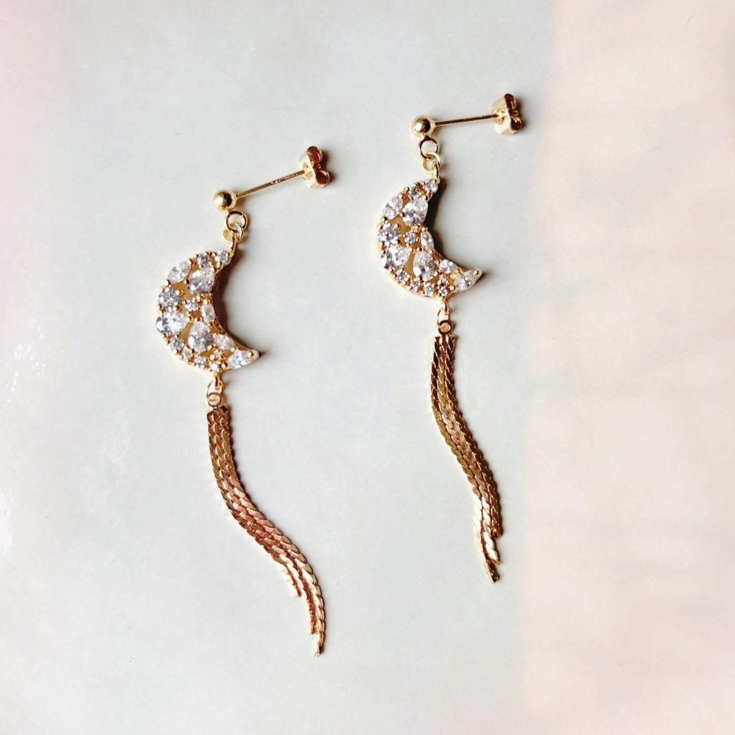 Boucles d’oreilles pendantes croissant de lune, délicatement serties de zircones scintillantes.