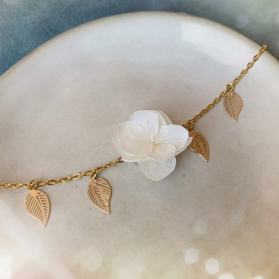 Bijoux mariage fleuris : bracelet délicat en hortensias blancs stabilisés, une pièce artisanale qui complète parfaitement une tenue de mariée élégante.