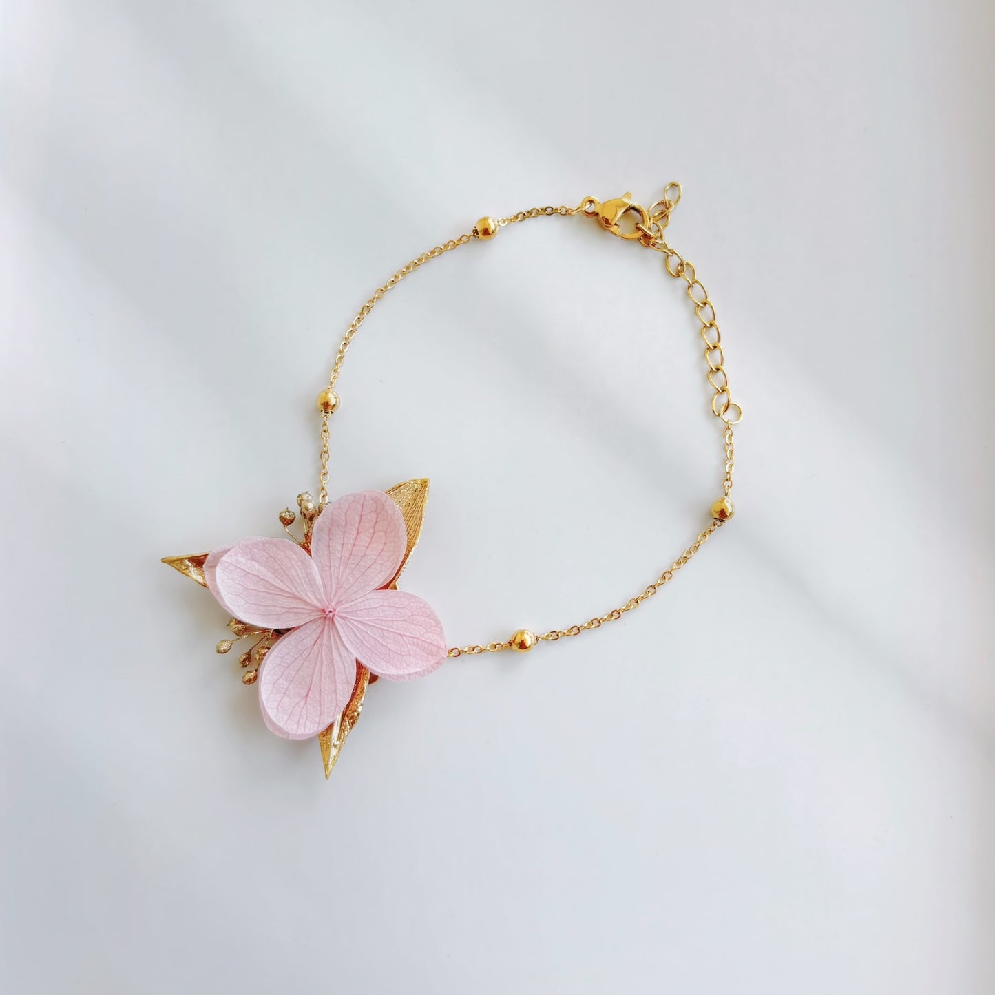 Création florale artisanale pour mariage, bracelet en hortensias stabilisés rouge et terracotta, signé Hana&Alice