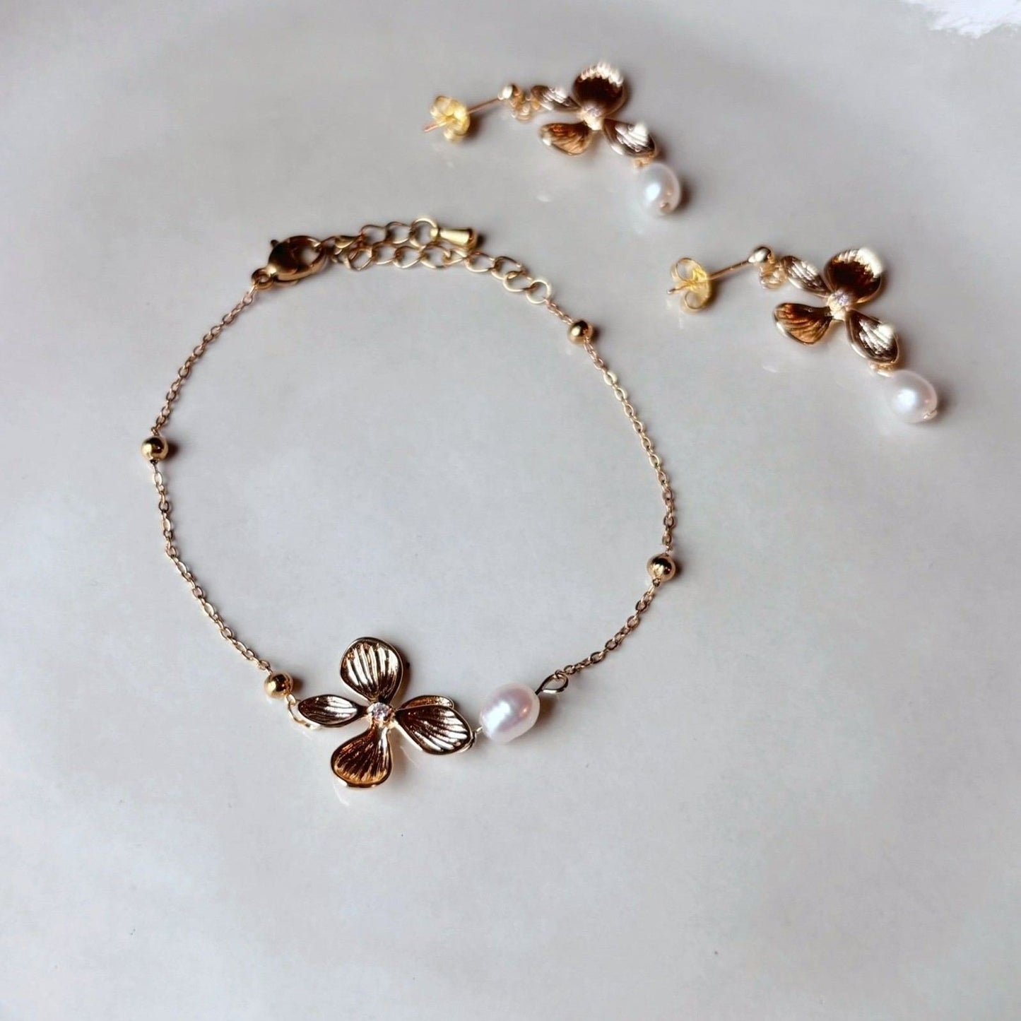 Bijou floral raffiné, bracelet doré avec perle d’eau douce et charme délicat.
