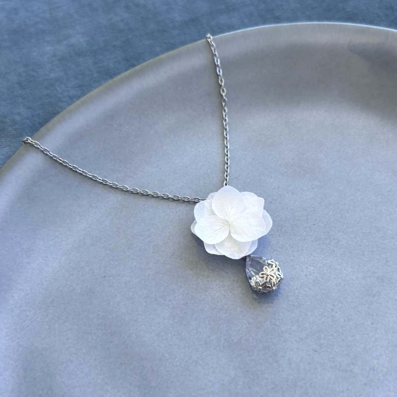 Collier pour mariage Hana&Alice, mêlant la beauté naturelle des hortensias stabilisés et le charme d’un pendentif cristal éclatant.