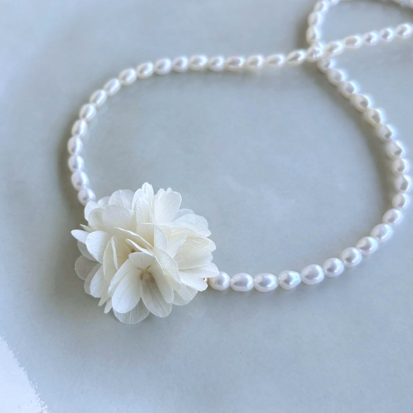 Collier mariage perle d’eau douce orné d’hortensias stabilisés, fait main par Hana&Alice.