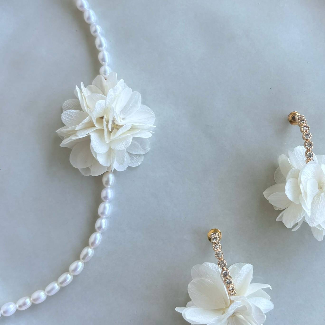 Bijoux mariage fleur stabilisée blanc crème, collier délicat en perles d'eau douce, création artisanale.