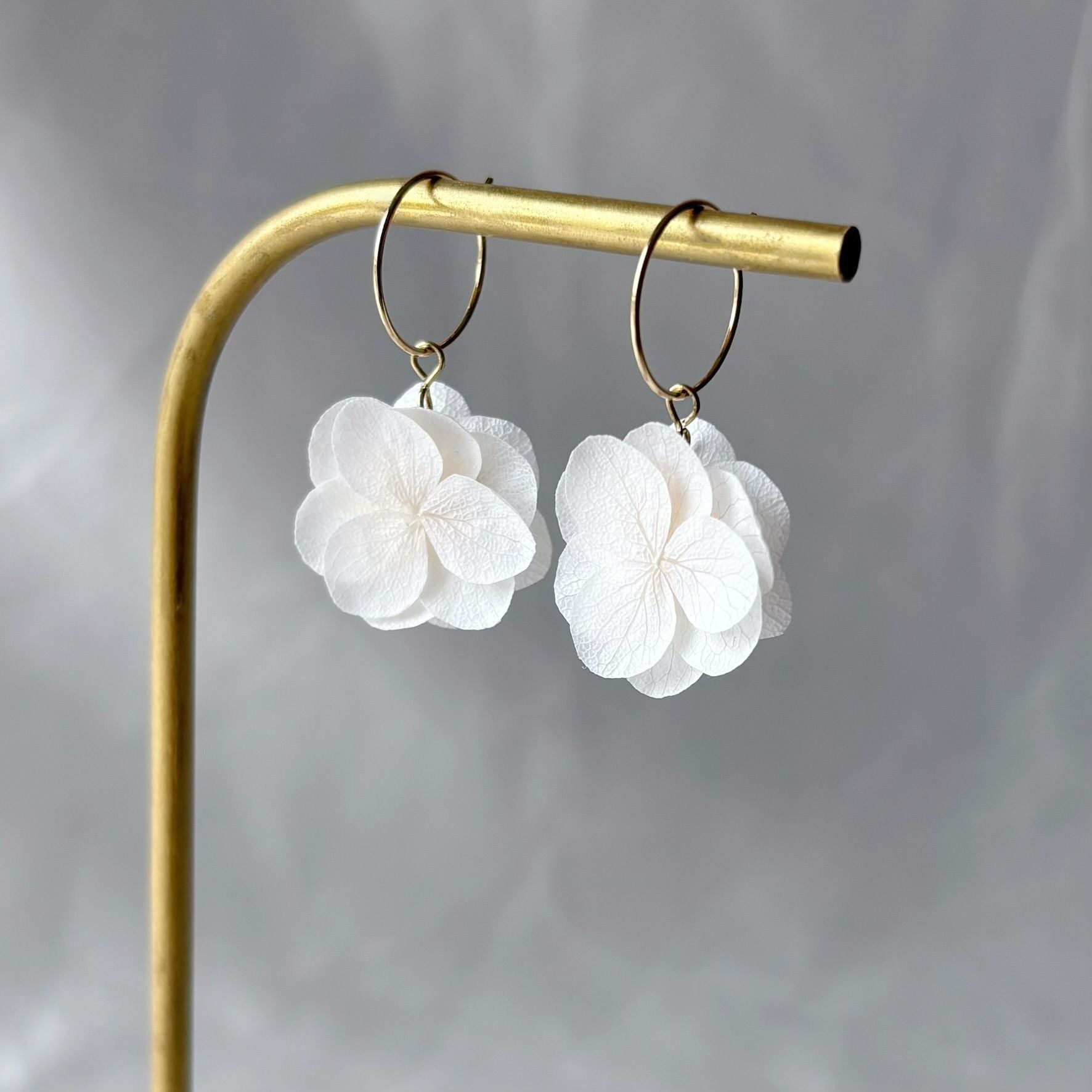 Bijoux mariage élégants : créoles ornées de fleurs d'hortensia stabilisées en blanc crème.
