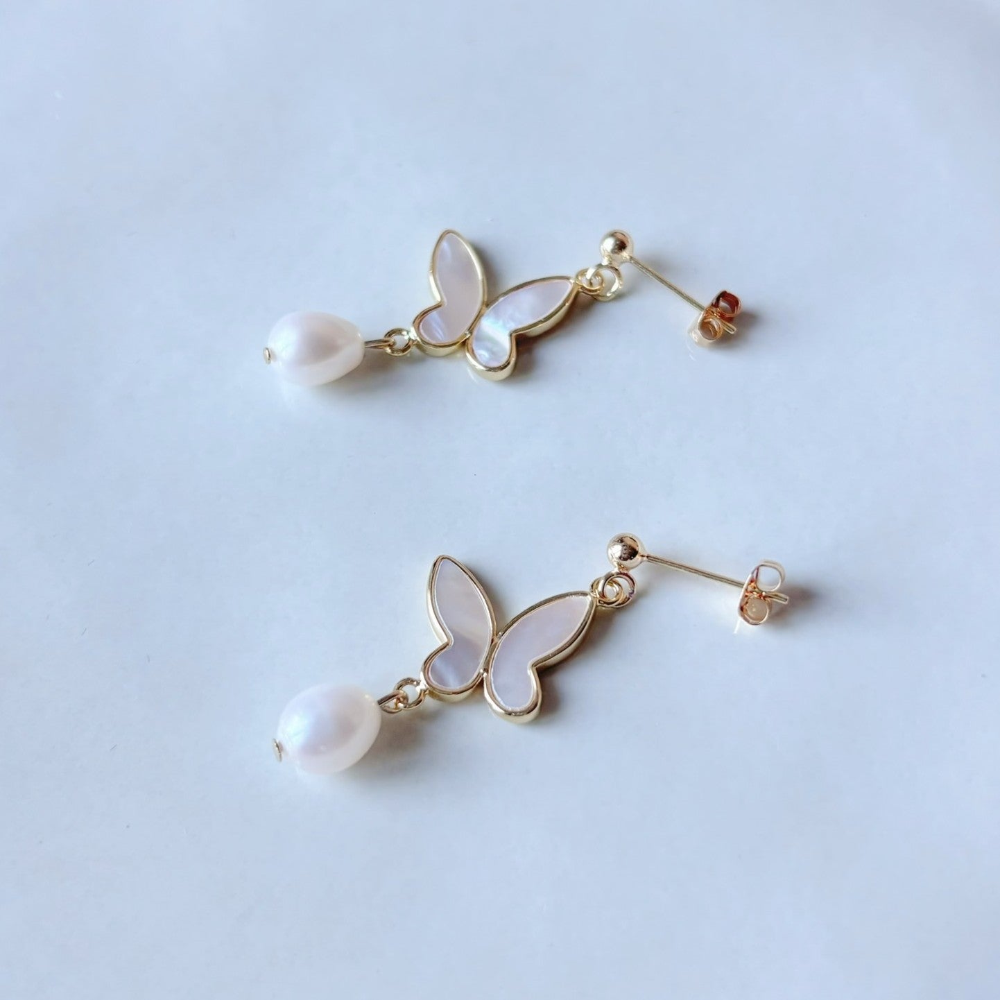 Boucles d’oreilles mariage perle et papillon, bijou classique à l’éclat poétique.