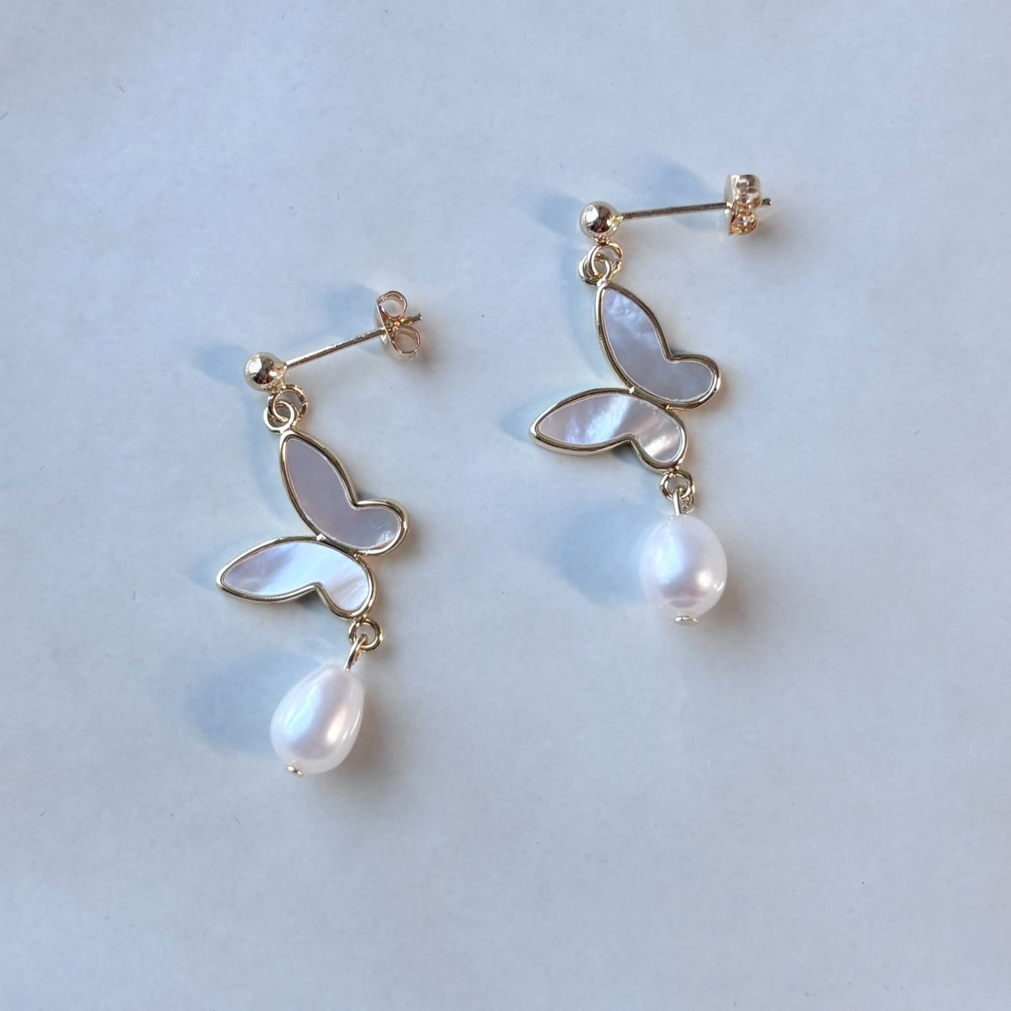Boucles d’oreilles mariage perle et papillon, bijou classique à l’éclat poétique.