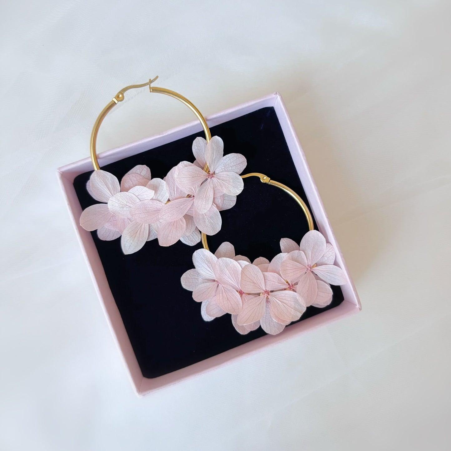 Bijoux créoles mariage avec hortensias stabilisés, accessoires floraux pour mariée et invités.