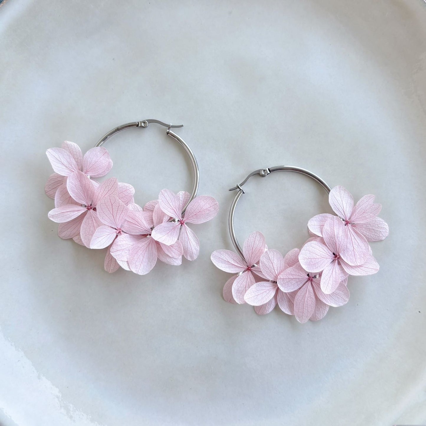 Bijoux créoles mariage avec hortensias stabilisés, accessoires floraux pour mariée et invités.
