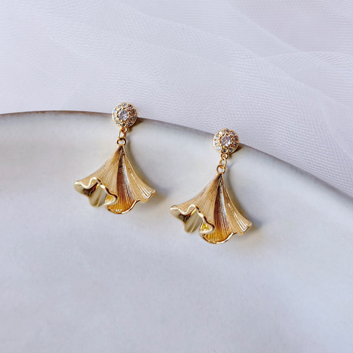 Boucles d’oreilles dorées avec clous sertis de zircons et pendentif ginkgo