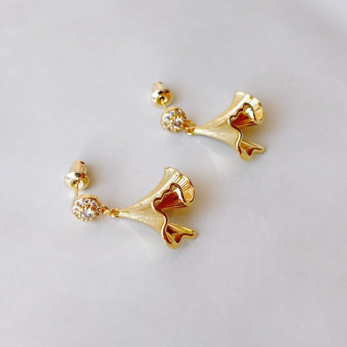 Détail des boucles d’oreilles avec mini zircons et pendentifs en forme de feuilles de ginkgo