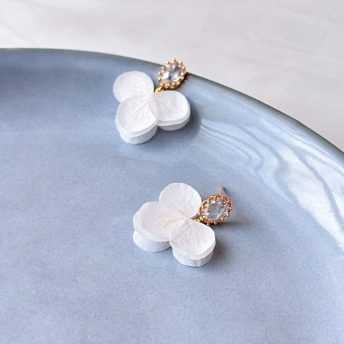 Boucles d’oreilles faites main pour mariée avec fleurs stabilisées blanches et détails scintillants