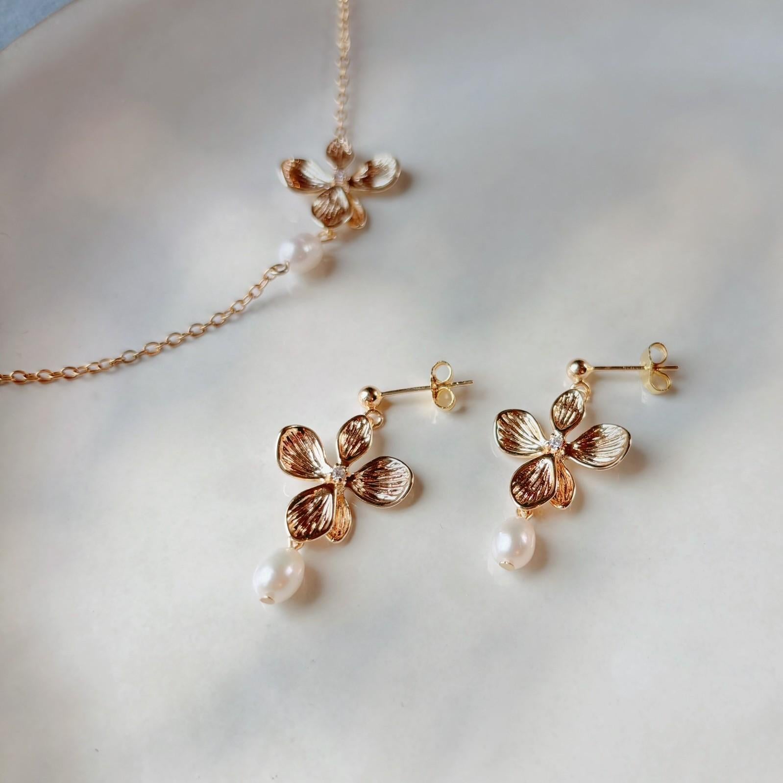 Boucles d’oreilles élégantes pour invitée de mariage, à fleur dorée et perle naturelle.