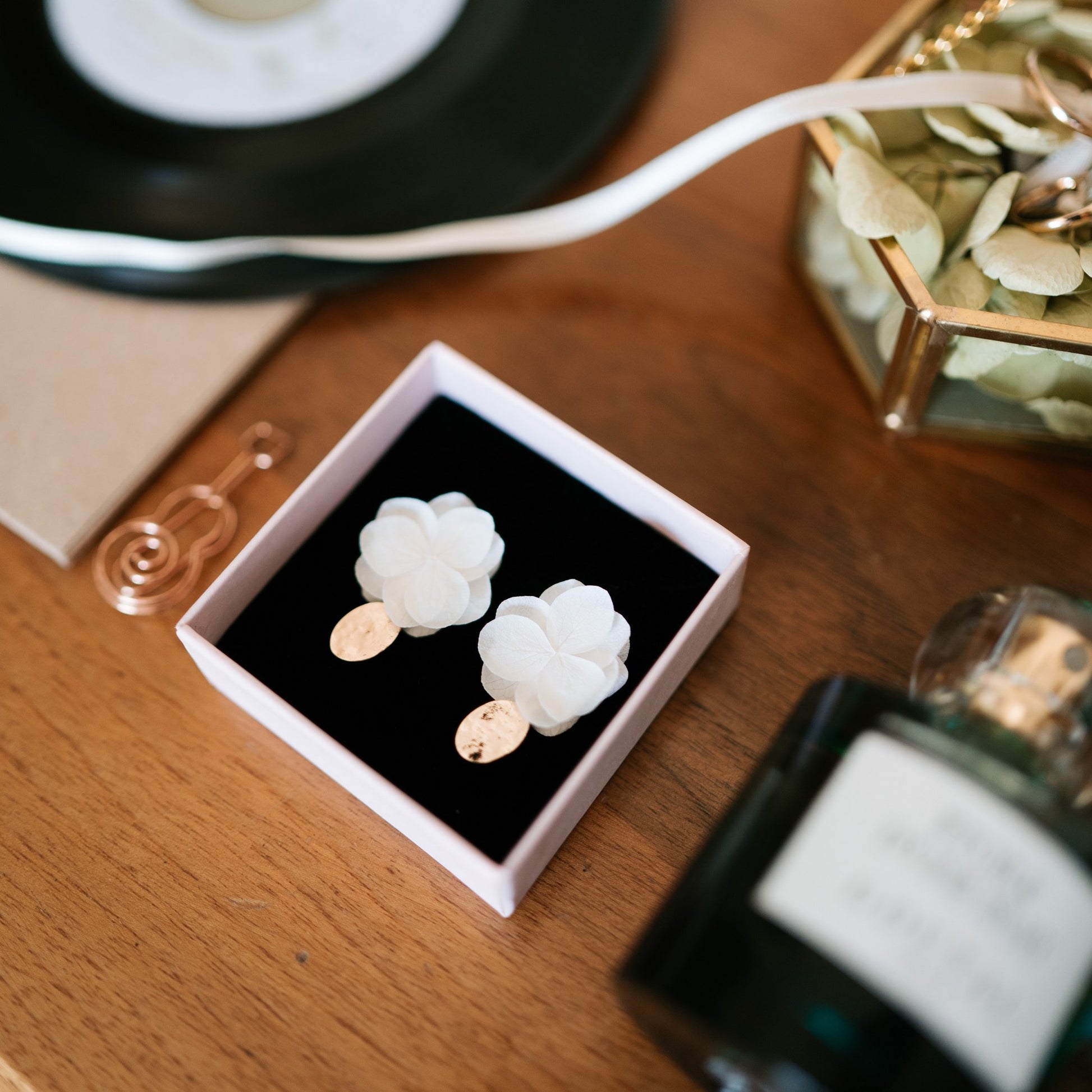 Boucles d'oreilles mariage élégantes en doré martelé avec pétales d’hortensias stabilisés, des bijoux fleuris signés Hana&Alice.