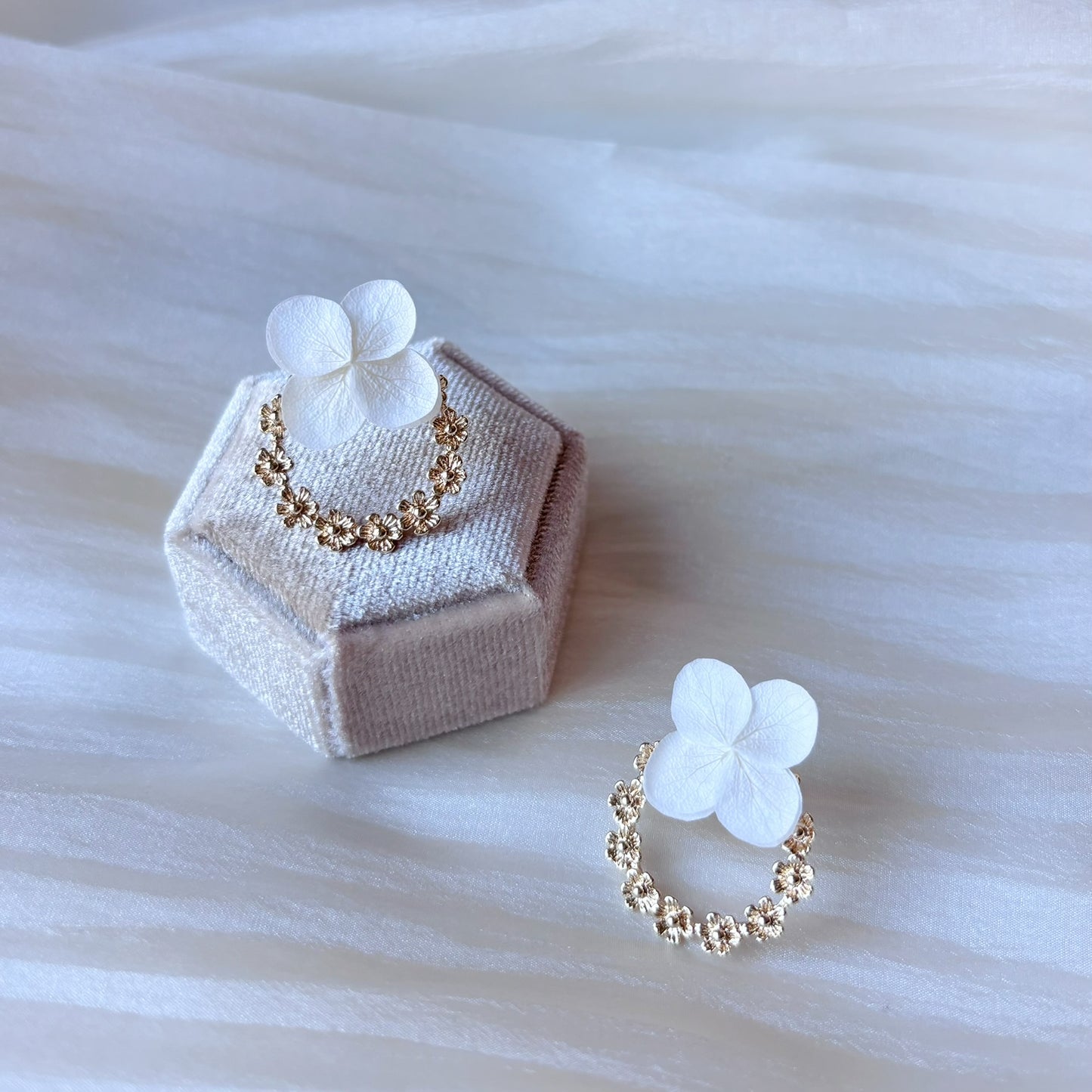 Bijoux mariage élégants : boucles d’oreilles avec fleurs stabilisées et couronne dorée délicate.