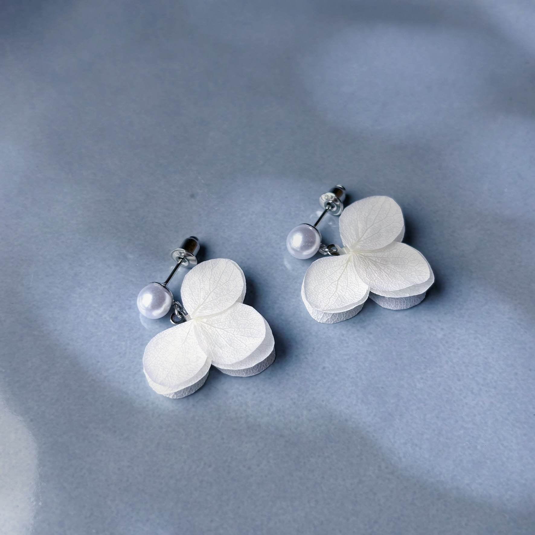 Élégantes boucles d'oreilles avec perles et hortensias stabilisés, parfaites pour sublimer une tenue de mariage ou d’anniversaire avec Hana&Alice.