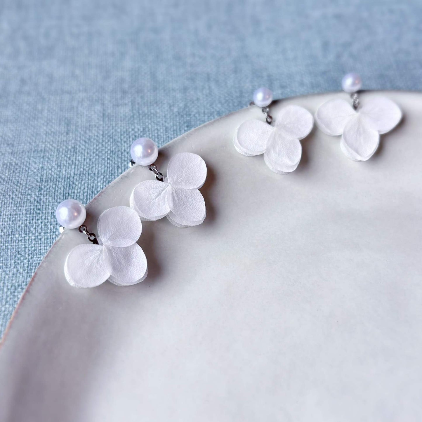 Bijoux mariage élégants en hortensias stabilisés blancs et perles, conçus pour sublimer votre tenue avec une touche florale et raffinée.