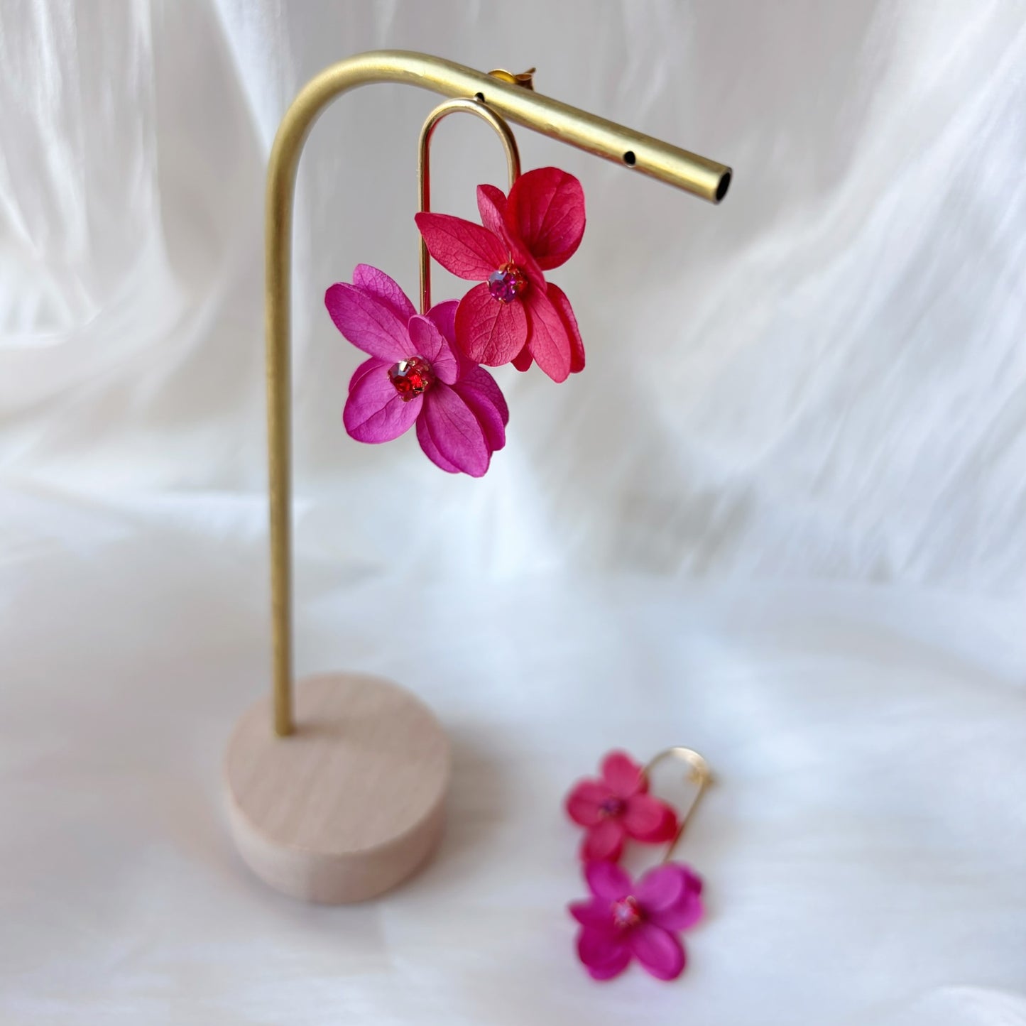 Boucles d’oreilles mariage délicates en fleurs stabilisées rouge et fuchsia avec strass scintillants.