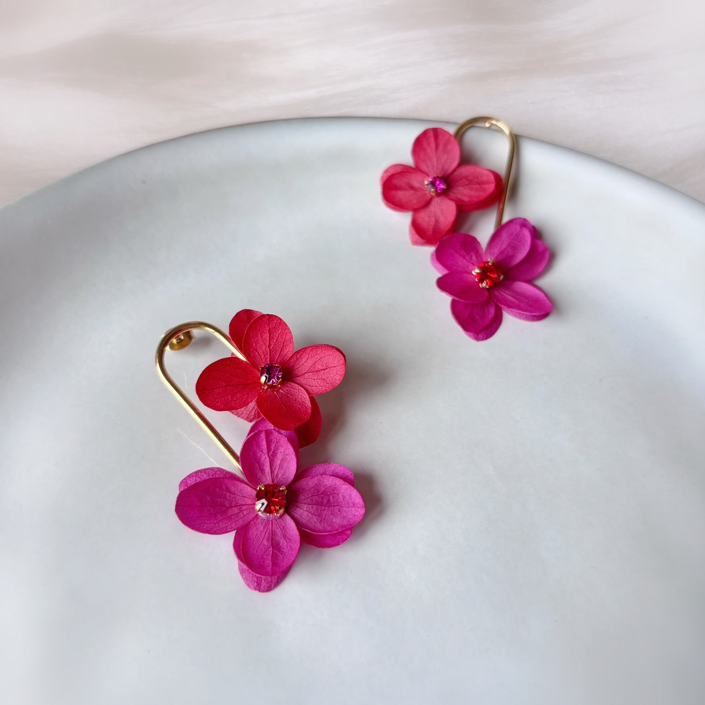 Boucles d’oreilles artisanales Hana&Alice en hortensias stabilisés rouge et fuchsia, bijou mariage délicat.