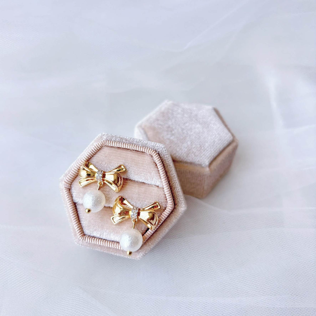 Boucles d’oreilles lumineuses avec nœud doré orné de zircons et perle ronde