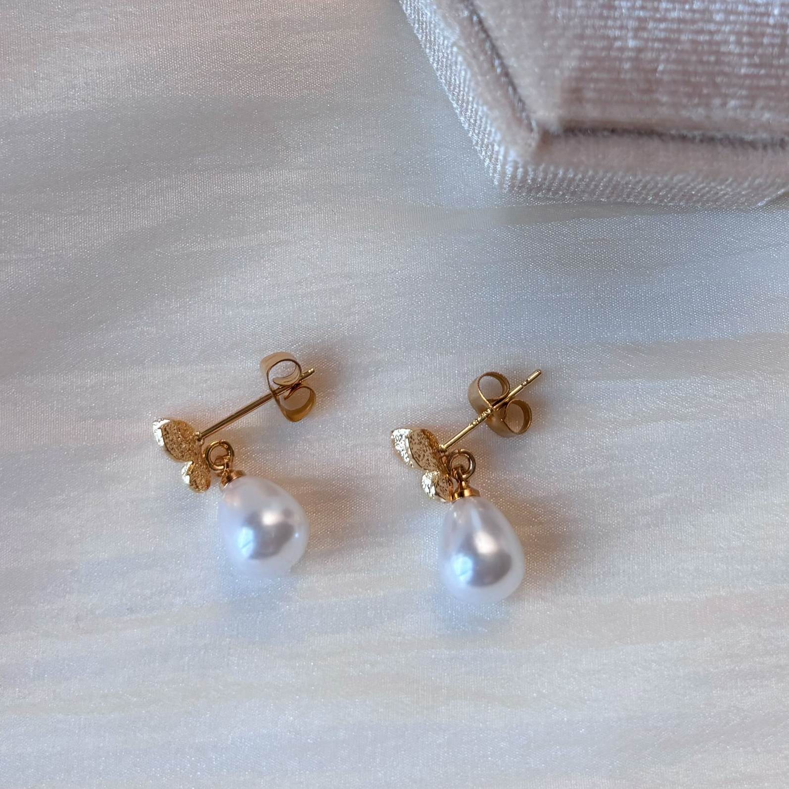 Découvrez les boucles d'oreilles papillon perle de Hana&Alice, pour un mariage plein de charme.