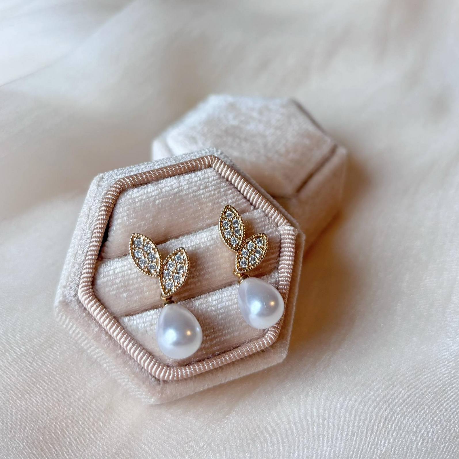 Création artisanale de boucles d’oreilles dorées à perle blanche.