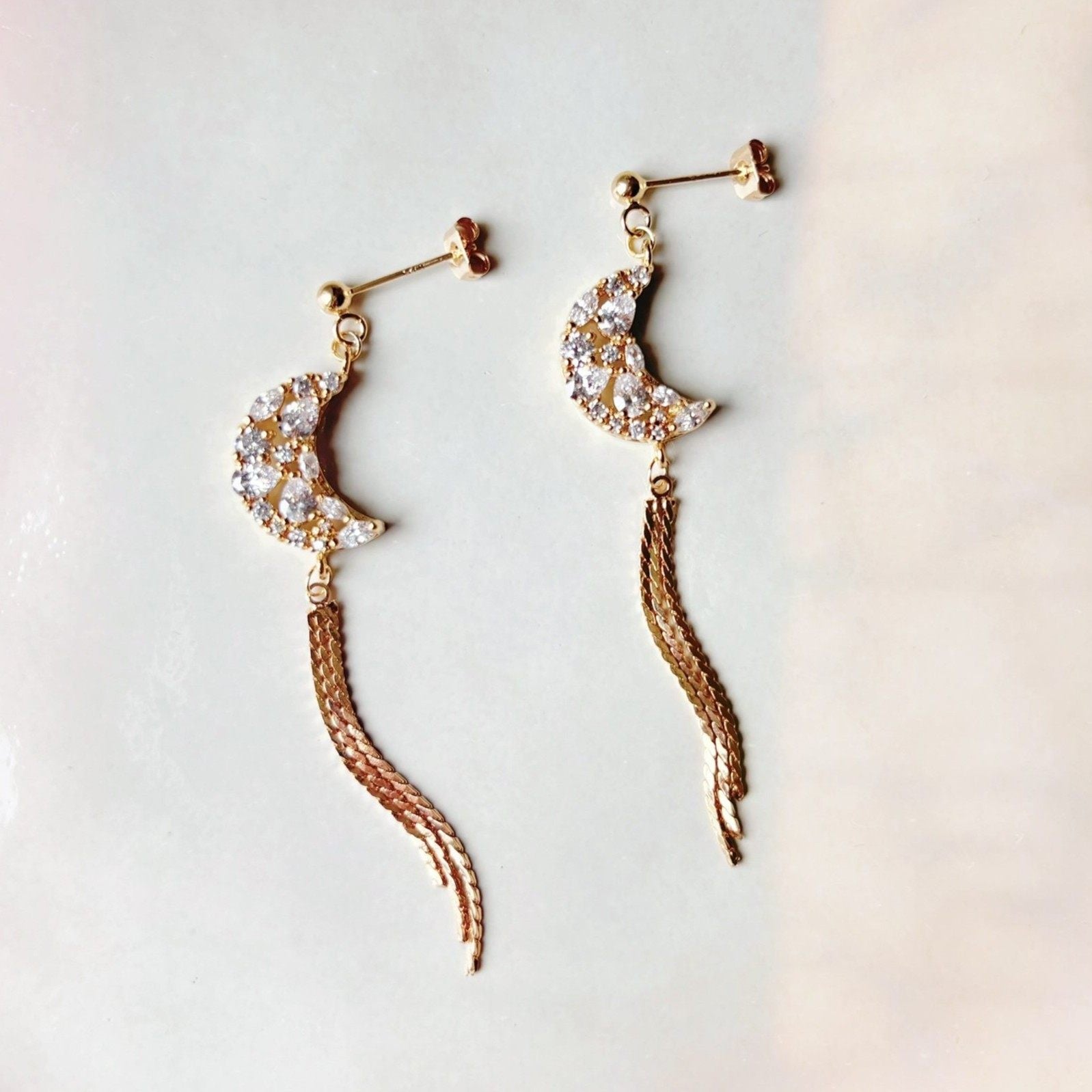 Boucles d’oreilles pendantes croissant de lune, délicatement serties de zircones scintillantes.