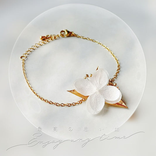 Bracelet mariage bohème chic en fleurs stabilisées blanches et feuilles dorées.