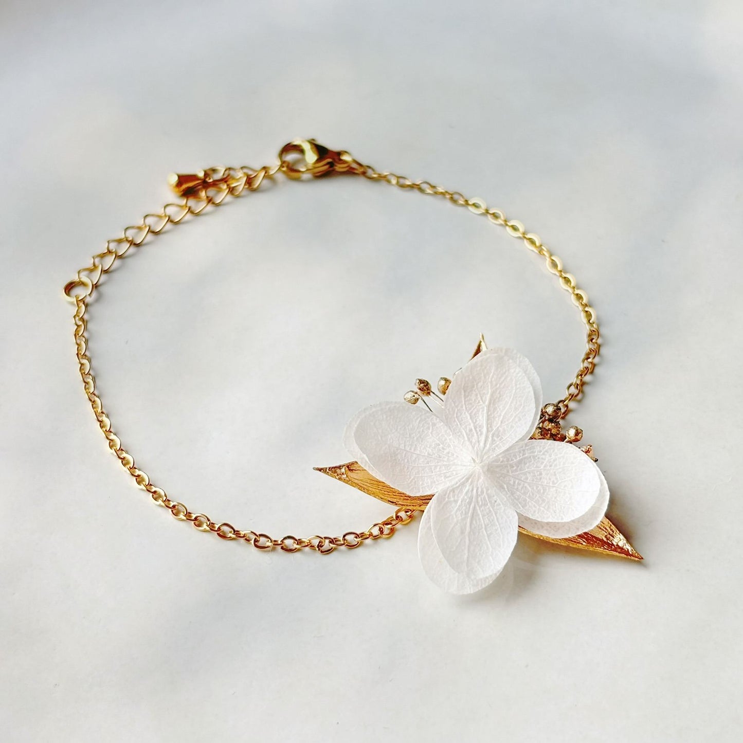 Bracelet mariage élégant en hortensia stabilisé et feuilles dorées.