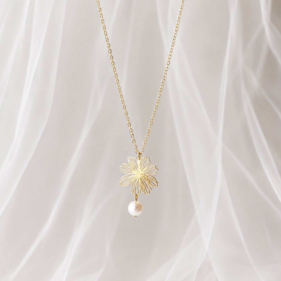 Gros plan sur les boucles d’oreilles mariage fleur dorée ajourée et perle ronde texturée