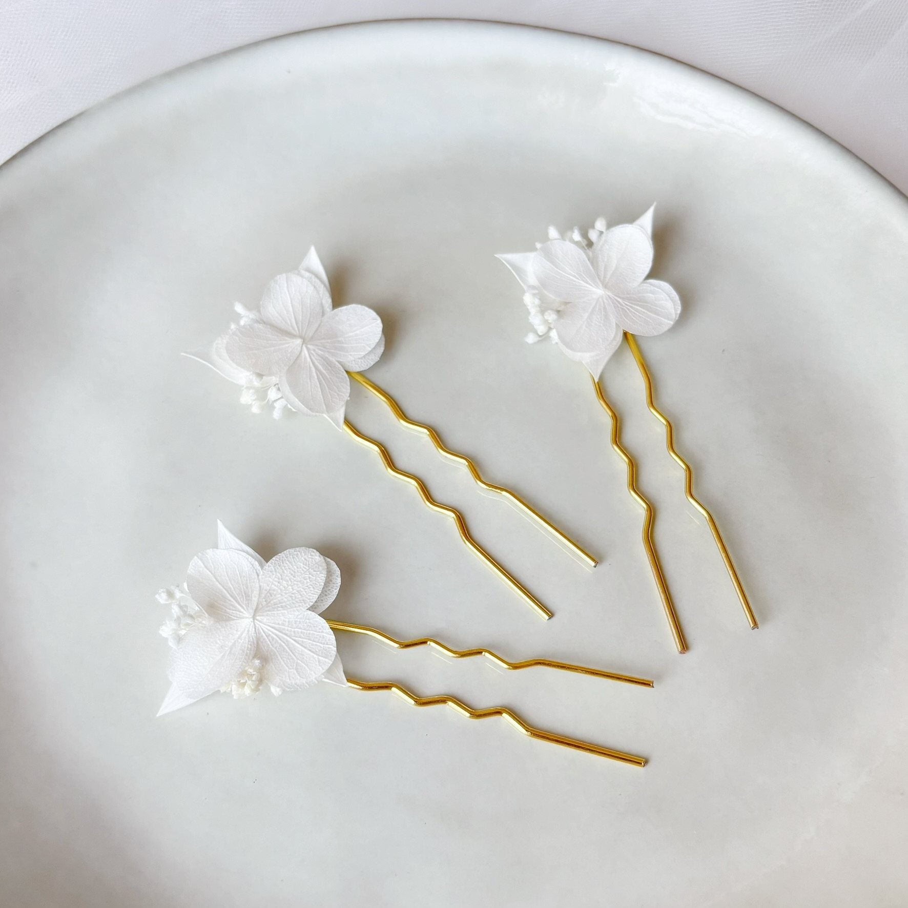 Épingles cheveux mariage bohème avec hortensias stabilisés blancs et fleurs séchées pour coiffure de mariée élégante